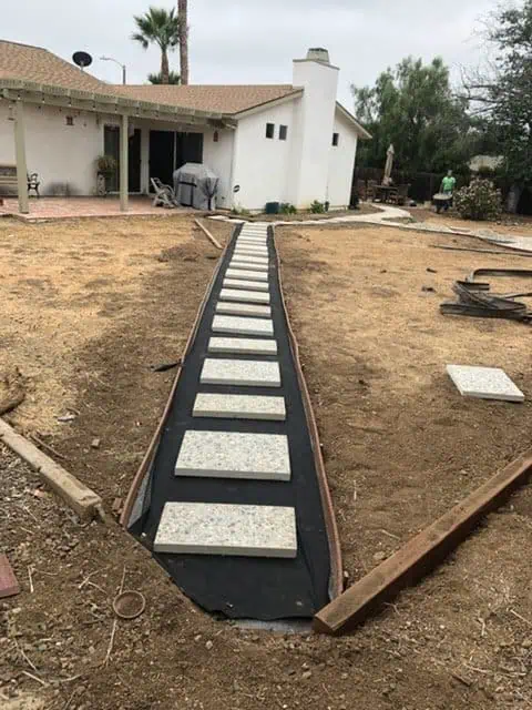 Concrete stepping stones being installed on a backyard pathway.