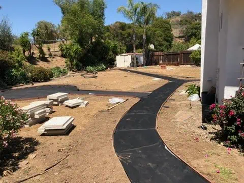 Curved black pathway being installed in a garden landscape at The Geranium.